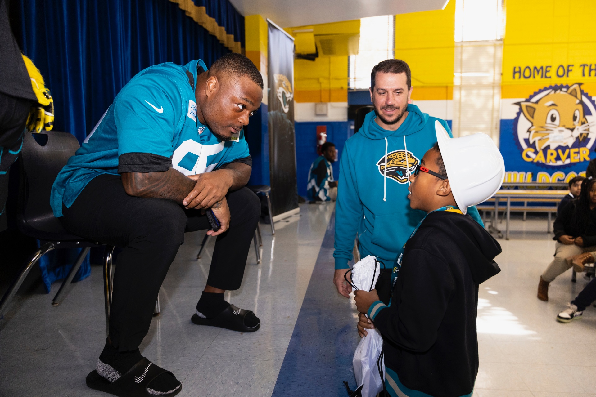 BJ Green kneeling to talk with a young student during a school visit