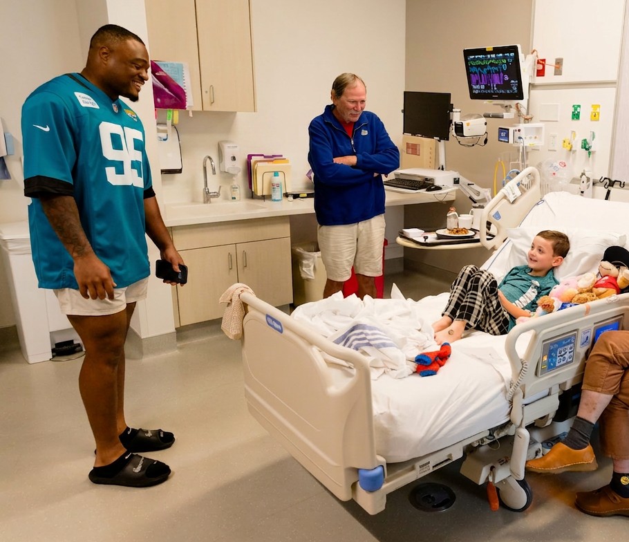 BJ Green and teammates visiting a smiling young patient at his hospital bedside